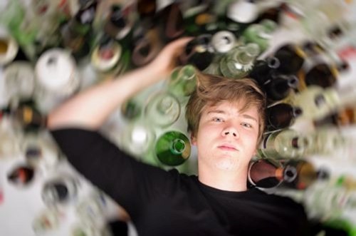teen boy laying next to beer bottles