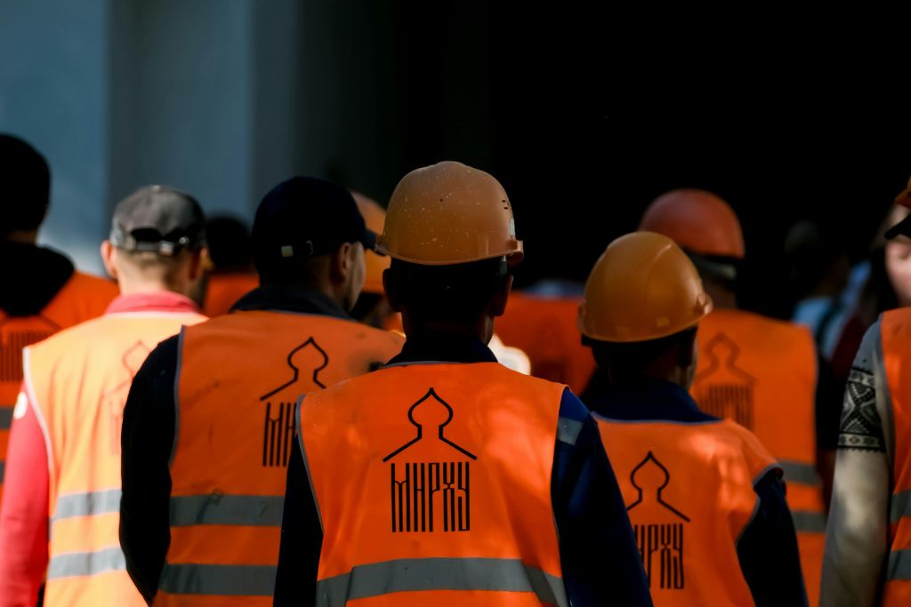 Group of construction workers in orange safety vests and helmets walking together — representing Idaho supervisors preparing for reasonable suspicion training with mock scenarios and role-playing.