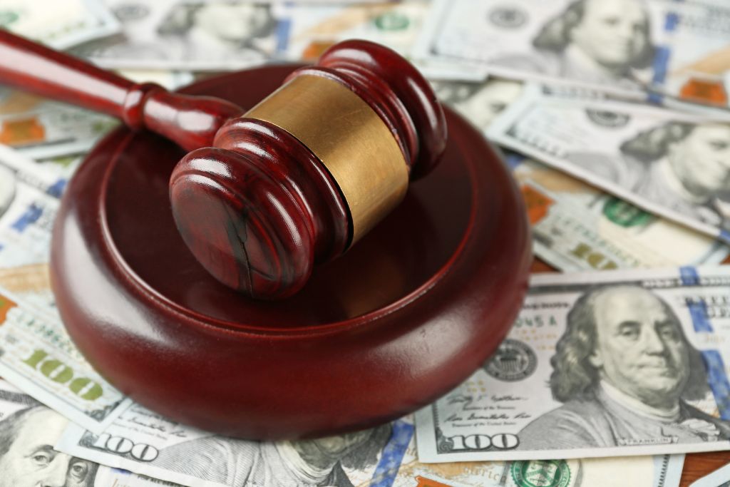 Judge’s gavel resting on dollar bills symbolizing the high cost of workplace lawsuits and the value of strong drug testing documentation for defense.