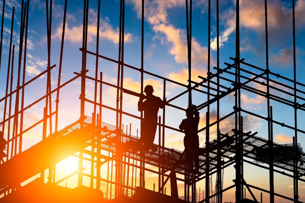 Silhouette of construction workers on scaffolding during sunrise in Boise Idaho, representing workplace safety, insurance savings, and liability protection through drug testing programs.