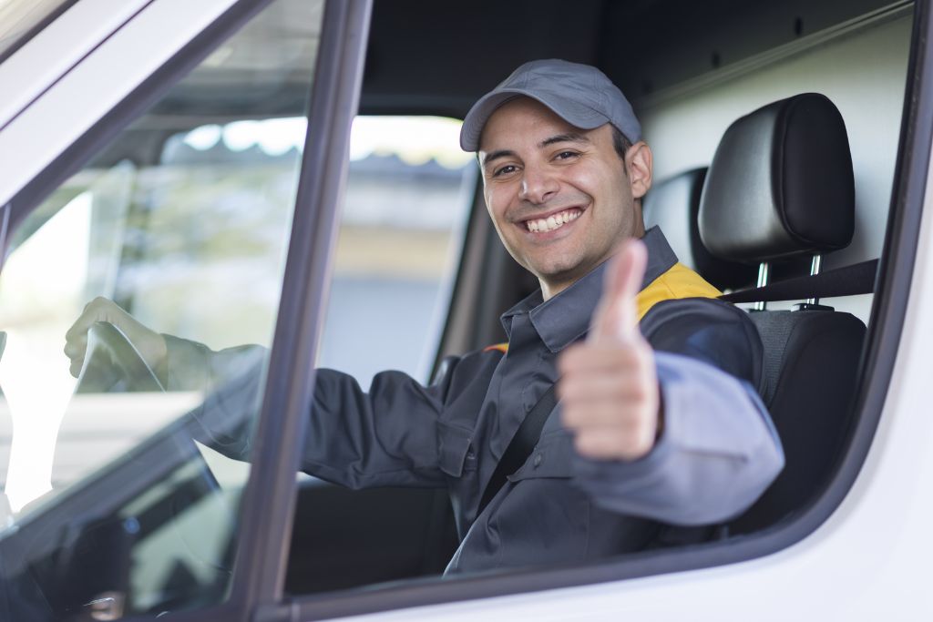 Smiling delivery driver giving a thumbs-up from his vehicle, representing a safe and compliant workforce supported by effective reasonable suspicion documentation.