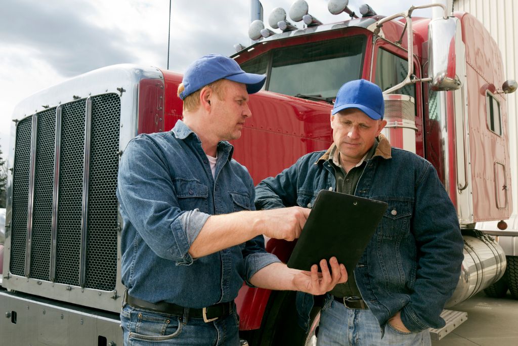 Boise trucking supervisors reviewing a clipboard in front of a semi-truck, highlighting professional documentation and confidentiality in reasonable suspicion drug and alcohol testing